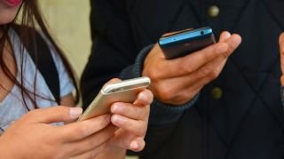 Zwei Personen, die auf Smartphones SMS schreiben