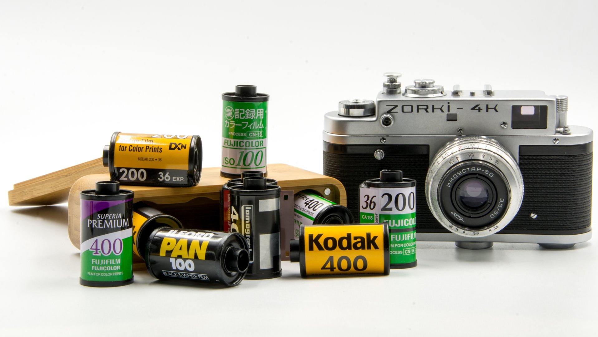 Un grupo de negativos de película de 35 mm de Fujifilm y Kodak junto a una cámara rusa 4K Zorki