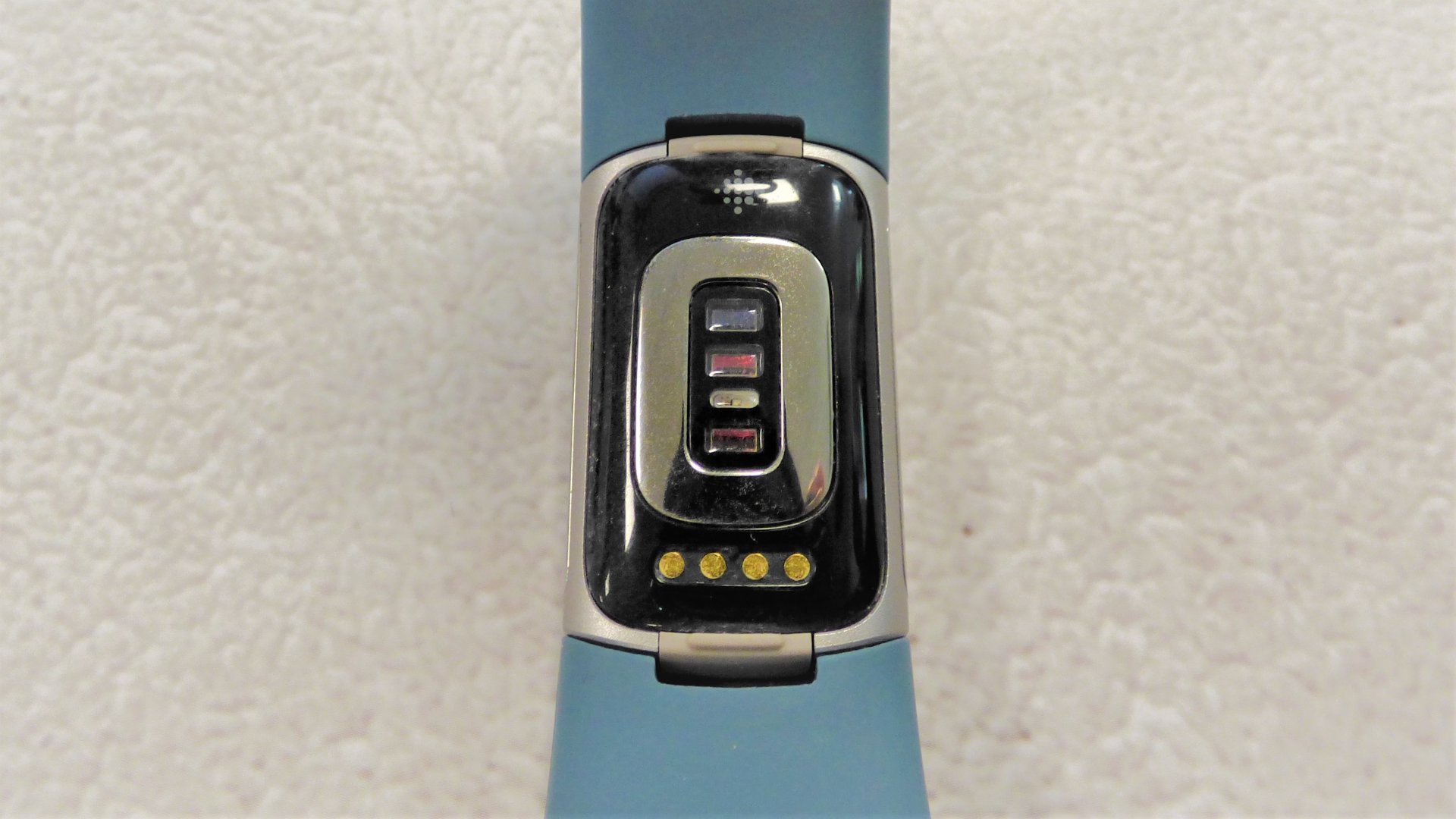 Parte posterior de Fitbit Charge 5, que muestra el sensor óptico y los conectores de carga