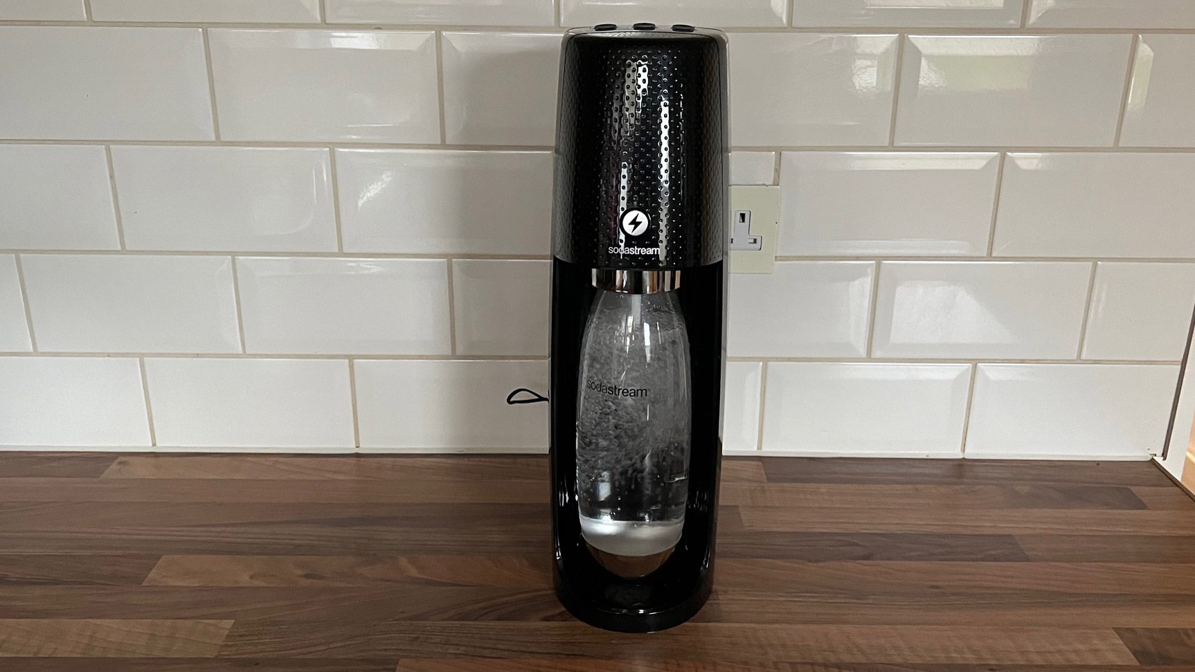 The Sodastream Spirit One Touch in the middle of carbonated water on a kitchen counter