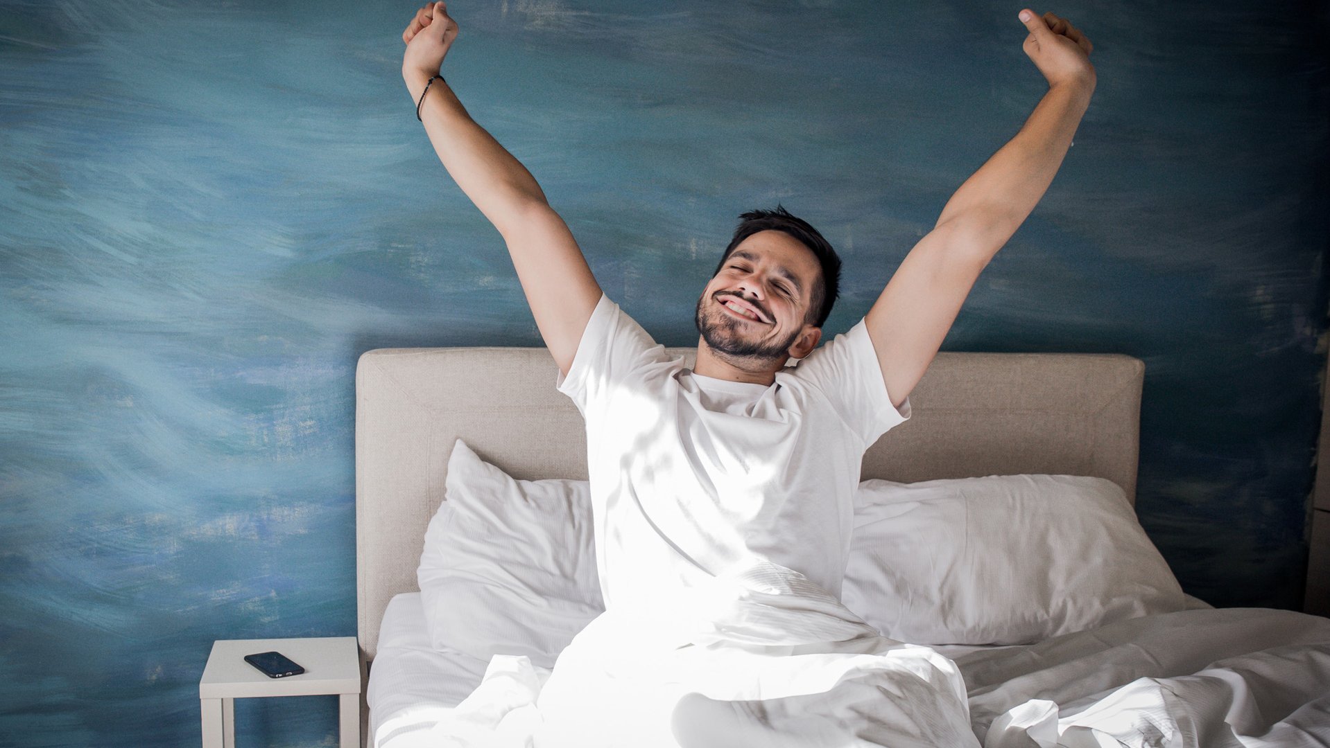 Un uomo si sveglia felice dopo una buona notte di sonno.