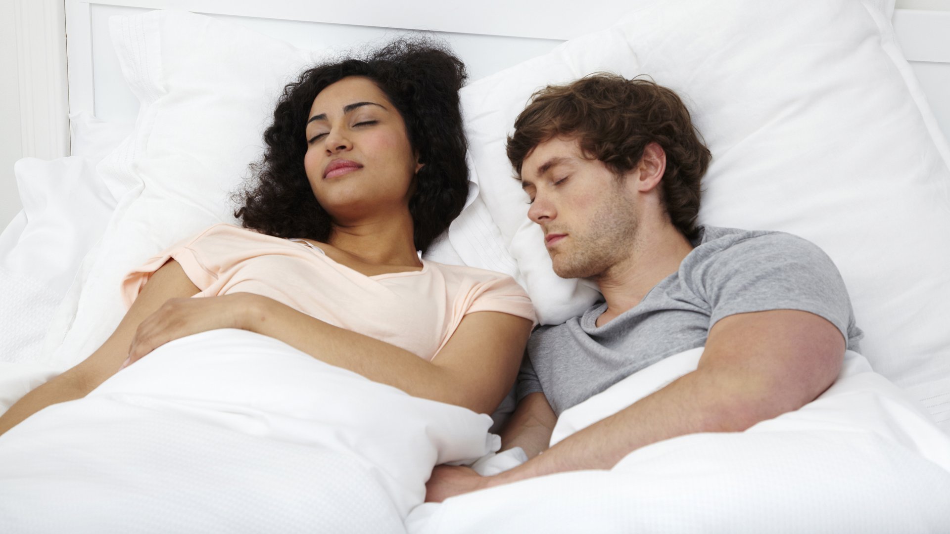 Zdjęcia przedstawiają parę śpiącą razem w łóżku, spoczywającą na białych poduszkach.