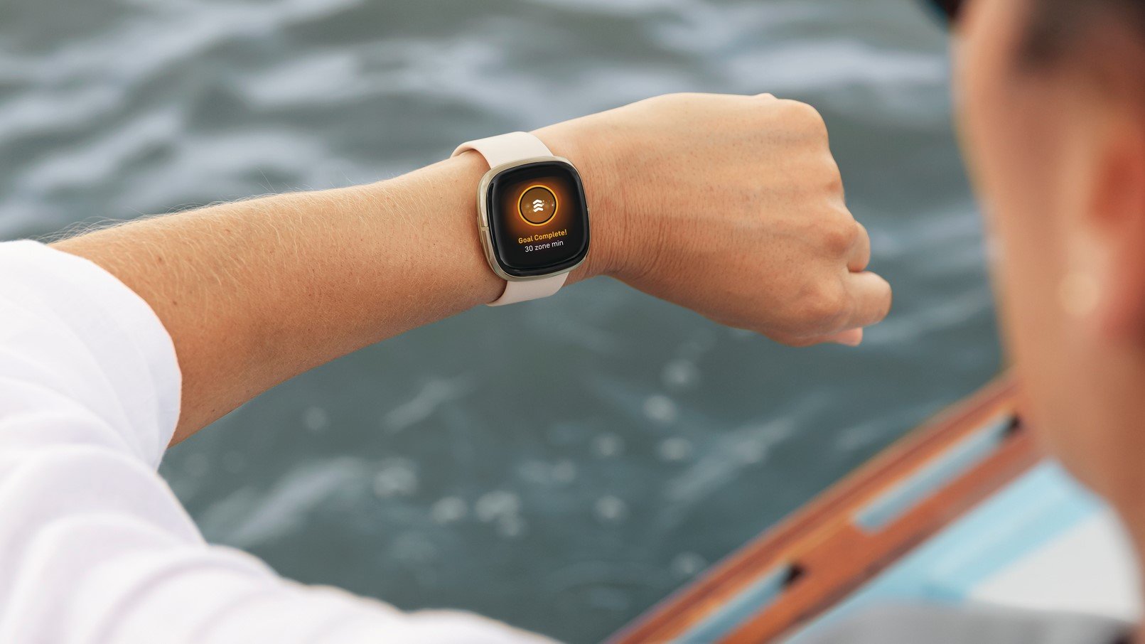 Женщина на лодке проверяет свои часы Fitbit Sense