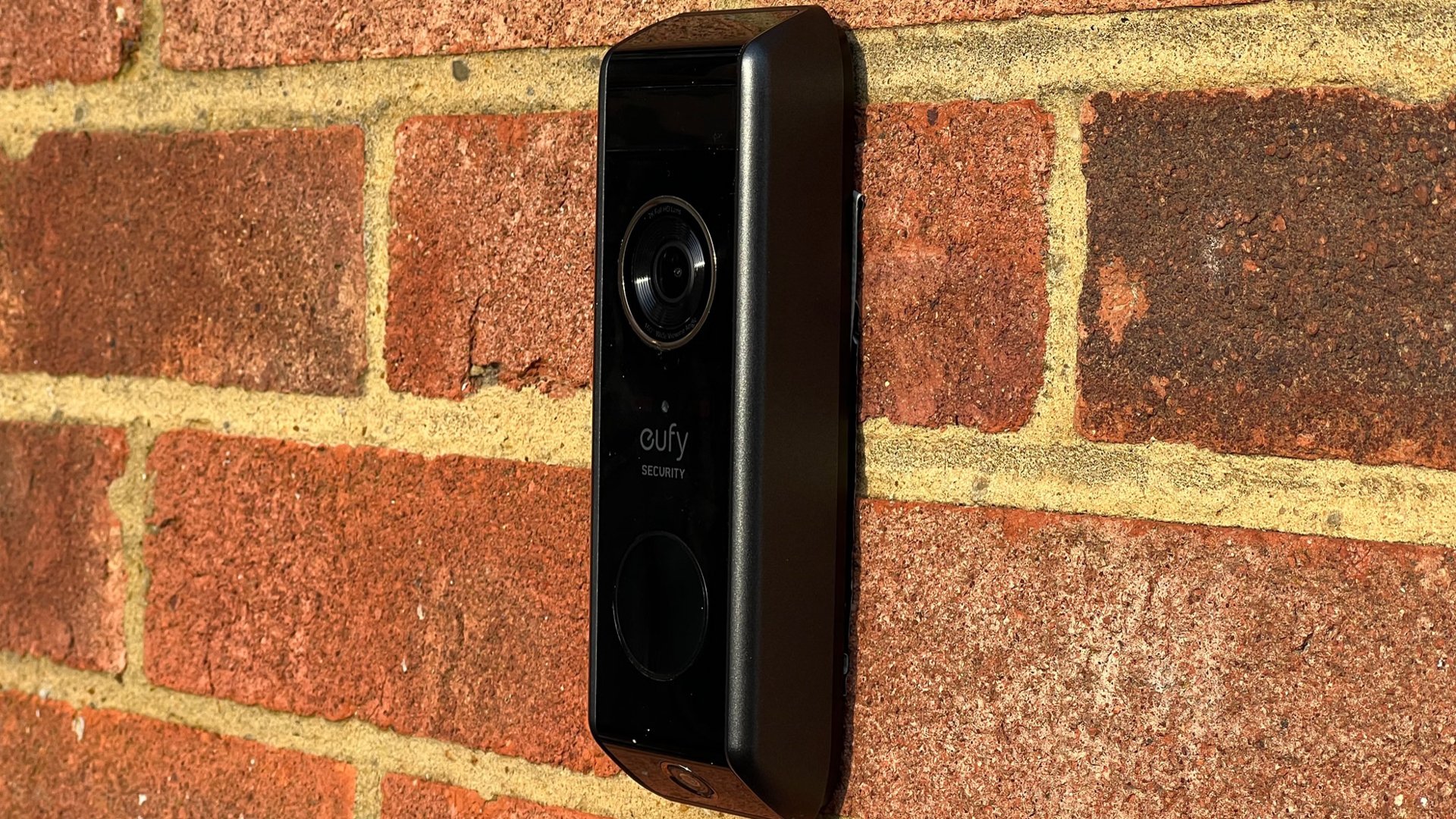 Вид сбоку на дверной звонок Eufy Dual Video на кирпичной стене.