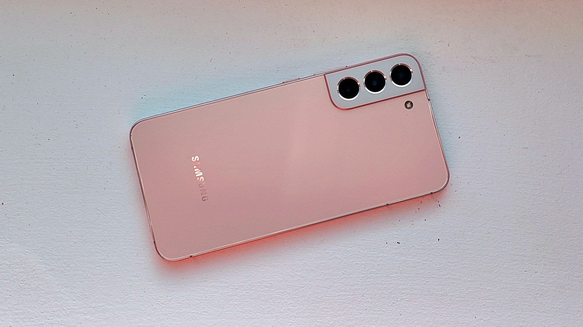 Un Samsung Galaxy S22 Plus rosado desde atrás sobre una superficie blanca