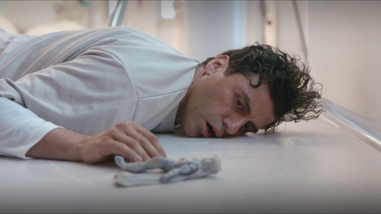 Marc Spector est allongé sur le sol d'un hôpital psychiatrique avec une figurine articulée Moon Knight dans l'émission Disney Plus