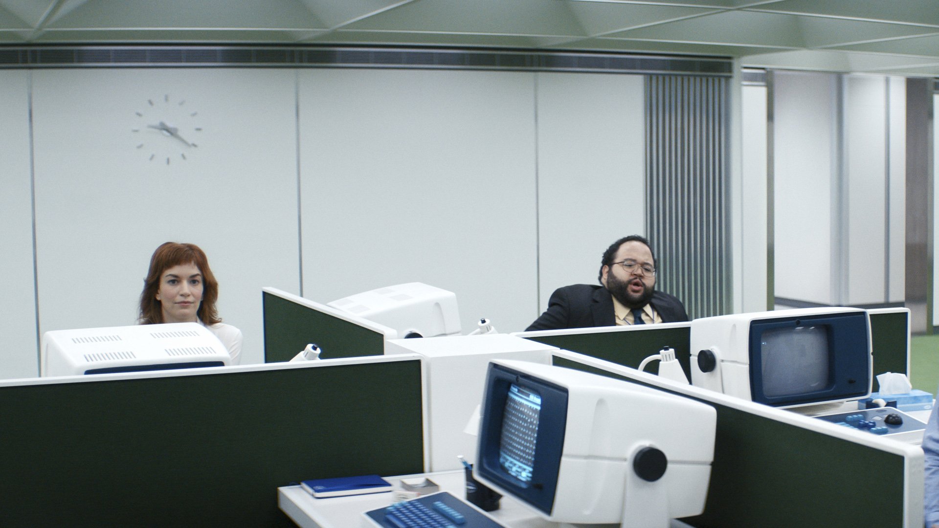 Deux employés de Lumon Industries lèvent les yeux de leur bureau dans Severance saison 1